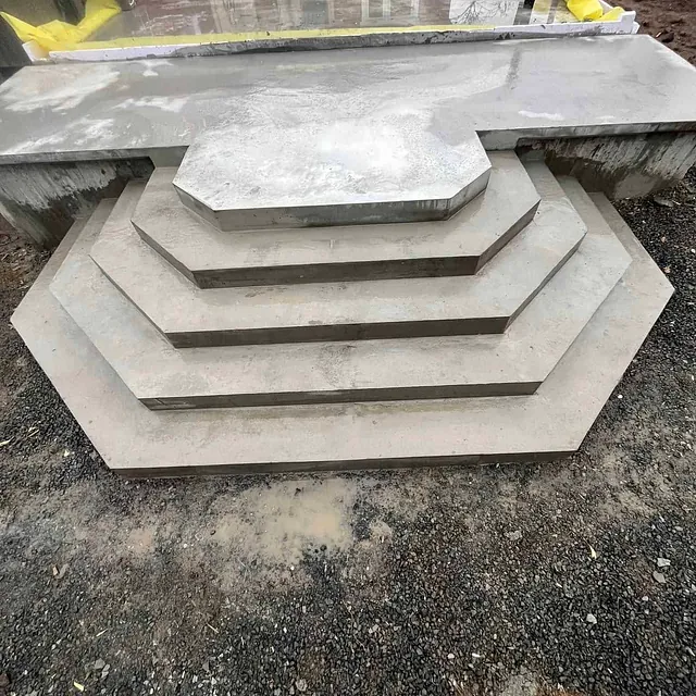Trapp med fem brede betongtrinn i moderne design, foran nytt betonggulv ved inngang.